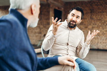 Businessman actively gesturing while explaining something to senior colleague