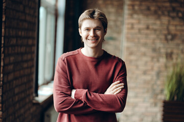 Portrait of smiling young man with crossed arms in loft office