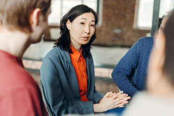 Asian businesswoman leading meeting with her team in office