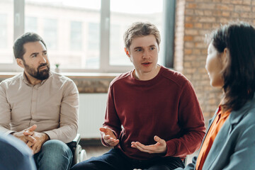 Handsome man sharing ideas during support group meeting
