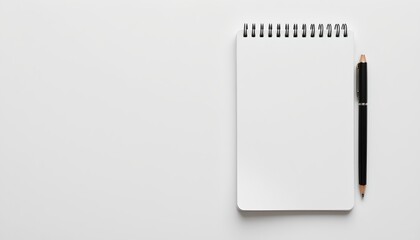 a simple, white spiral notebook with a black pen placed on top of it, resting open, revealing blank pages. the notebook is positioned in the foreground against a grey background.
