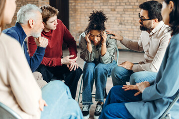 Psychotherapist comforting sad woman during group therapy session