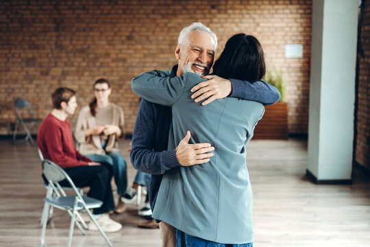 Senior man and businesswoman hugging during group therapy session