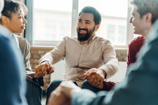 Diverse teammates holding hands during office meeting