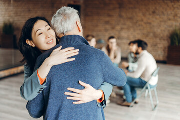 Asian businesswoman supporting senior man at group therapy session