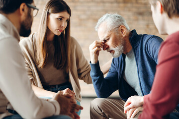 Senior man suffering from depression during group therapy session