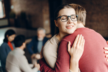 Happy young woman hugging man during psychotherapy session
