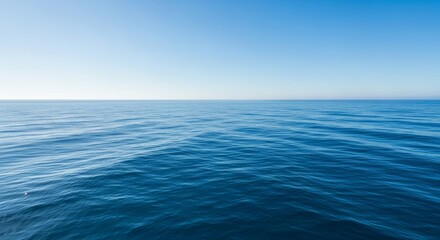 Obraz premium Calm ocean water reflects a gradient blue sky at midday
