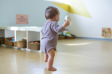 Baby boy try to walk indoor playground space