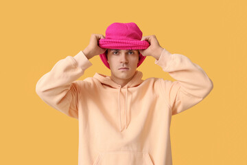 Handsome young man in balaclava on yellow background