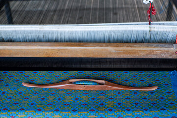 wooden bobbin on cotton loom, traditional handmade cotton weaving loom with textile pattern