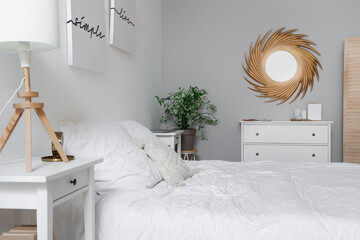 Comfortable bed, mirror and chest of drawers in room