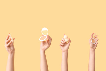 Female hands with sponge, lipstick and powder on yellow background