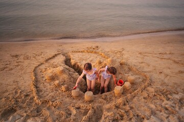 Siblings build an elaborate sandcastle on a sunny beach afternoon