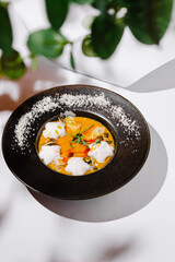 Delicate dish of colorful sauce with herbs served in a dark bowl