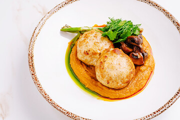 Tender chicken meatballs served over a smooth vegetable puree, accompanied by sauteed mushrooms, roasted asparagus, and fresh herbs, elegantly plated for a gourmet presentation.