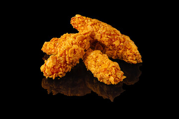 Delicious crispy fried chicken tenders on a black background