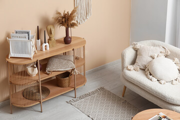 Comfortable sofa and shelving unit with different decor near beige wall in interior of modern...