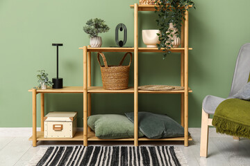 Modern shelving unit with rug, decor and armchair near green wall