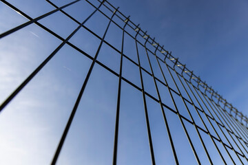 a thin metal lattice fence against a sky background, a small thin fence dividing the territory