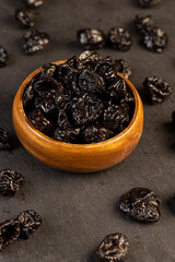 bowl filled with dried prunes closeup, dark dried plum fruits poured into a bowl