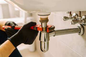 Plumber Using Pipe Wrench to Repair Sink for Home Plumbing Maintenance and Emergency Service
