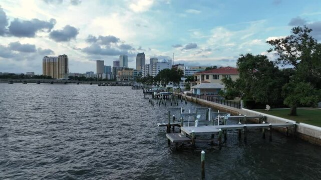 Aerial flight along luxury villas with private river access for boats in Tampa. Downtown skyline in background. Cloudy sunrise in the morning. Bayshore, Tampa, Florida.