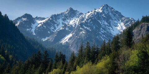 Obraz premium Majestic Snow Capped Mountains and Evergreen Forest Landscape in Spring