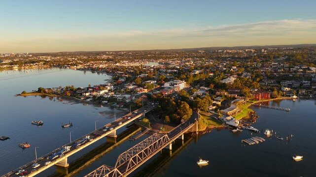 Aerial of Sylvania bridge and urban area with road traffic and boats in evening light, establishing overview, Sydney NSW Australia