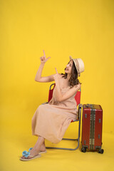 Traveler Sitting on a Chair with Luggage Against a Yellow Background