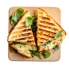 Grilled cheese sandwich cut in half on a wooden board with spinach leaves
