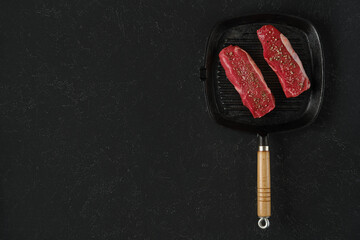Fresh cuts of beef steak on a griddle pan ready for cooking at a home kitchen