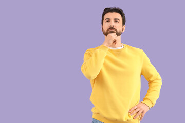 Thoughtful bearded man on lilac background