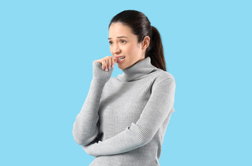 Portrait of worried young woman on blue background
