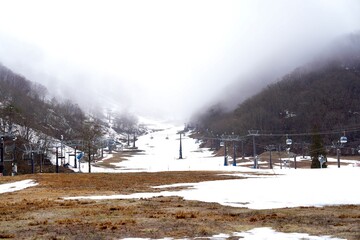 Patches of brown grass in late autumn several ski lift Hakuba Goryu Snow Resort is a popular ski resort located in the Hakuba Valley, Nagano.Winter Sports Park at the top of the mountain snowy slope.