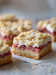 Close up of several strawberry crumble bars on white parchment paper in soft natural lighting