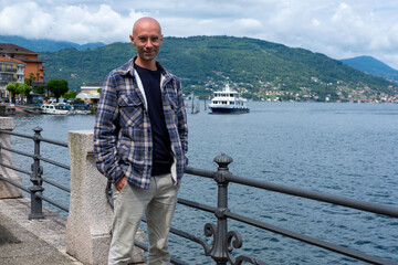 Young traveler man relaxing on Baveno promenade, man enjoying Marjorie lake view, summer breeze, peaceful moment, solo trip, scenic destination