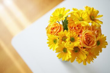 A vibrant bouquet of orange roses and yellow daisies arranged on a clean white surface with soft natural light