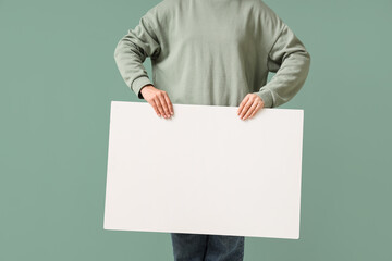 Young woman holding blank poster on green background