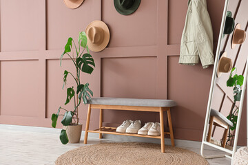 Interior of stylish hallway with soft bench, palm plant and mirror