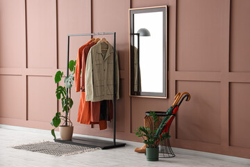 Interior of stylish hallway with coat rack, mirror and umbrellas