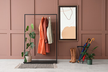 Interior of stylish hallway with coat rack, mirror and umbrellas