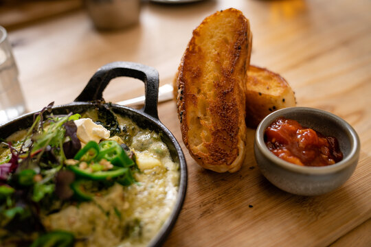 A classic shakshuka dish with poached eggs in a spicy tomato sauce, served with fresh herbs and toasted bread, perfect for breakfast, brunch, or Middle Eastern cuisine themes