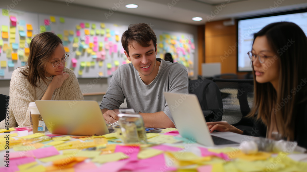 Poster team collaboration during a brainstorming session with laptops and colorful notes in a modern worksp