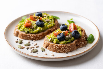 Avocado toast with blueberries, cherry tomatoes, sunflower seeds, pumpkin seeds, sesame seeds and other grain on plate, Healthy eating