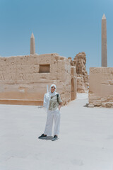 Tourist exploring karnak temple complex with obelisks and ancient walls in luxor, egypt
