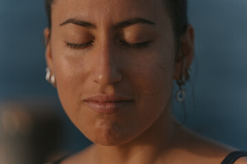Young woman closing eyes enjoying warm sunlight on face