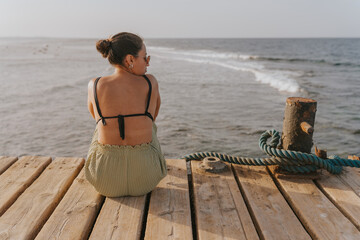 Tourist enjoying inspiring seascape while relaxing on wooden pier