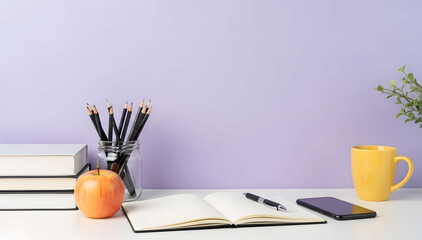 Study desk with apple, yellow mug, and stationery in front of purple wall