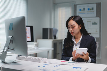 Businesswoman analyzing charts and using calculator in office